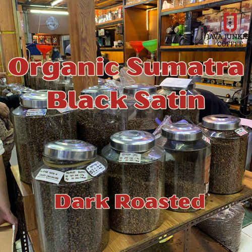Java Junkies Organic Sumatra Black Satin Coffee. Large canisters lined up in a coffee shop filled full of roasted coffee beans.