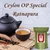 A dark clay teapot, a matching teacup filled with amber tea, and a wooden scoop of loose leaves resting on a bamboo mat.