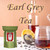 A glass jar filled with brewed Earl Grey tea sits beside a stainless steel mesh infuser, a vibrant lemon slice, and scattered loose tea leaves on a tabletop