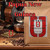 Java Junkies Papua New Guinea Coffee Bag. Pile of coffee beans from a spilled antique coffee roaster on a light brown table.