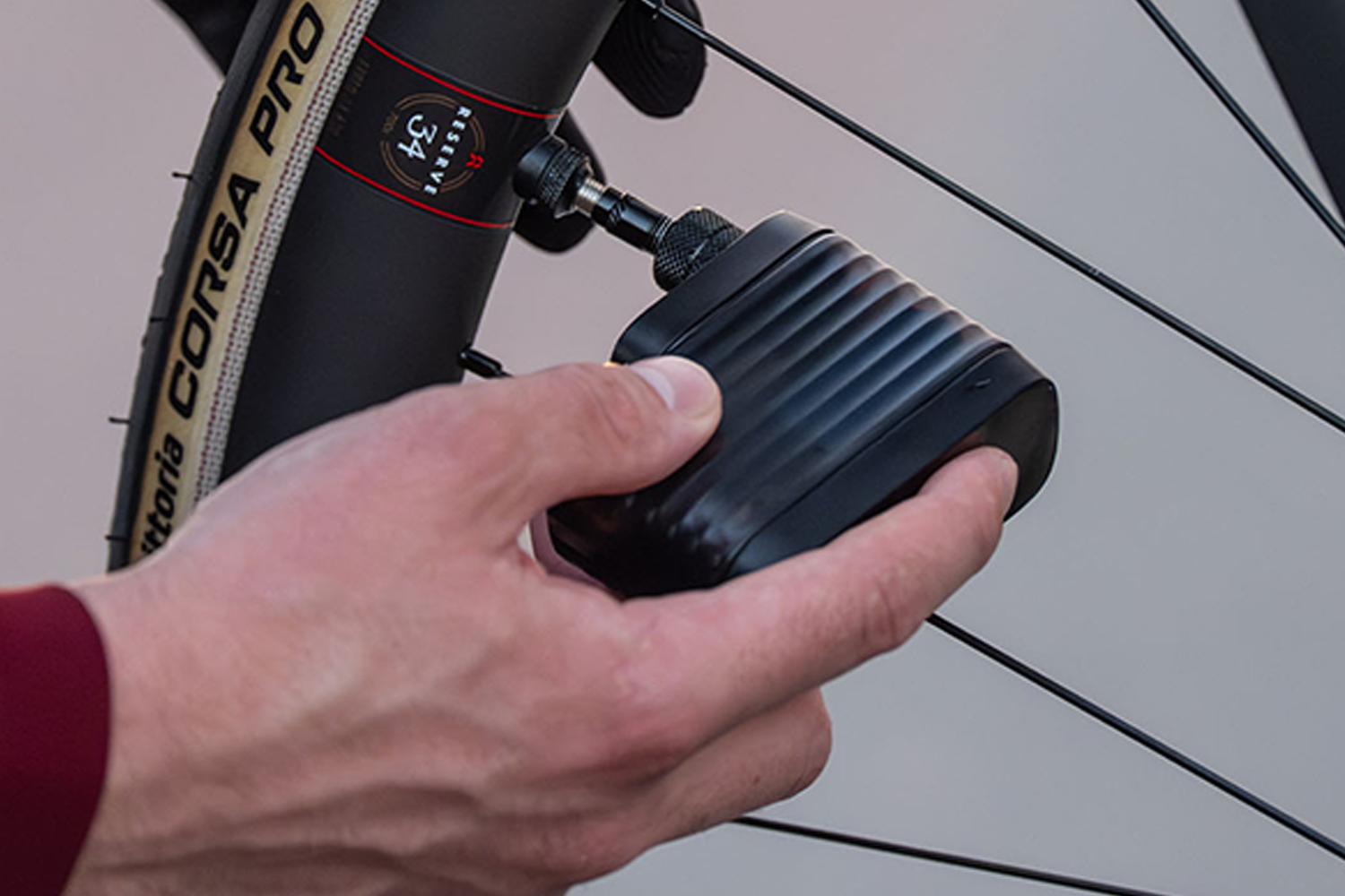 Cyclist using the BBB Cycling BarBank smart electric pump to inflate a road bike tyre valve. 