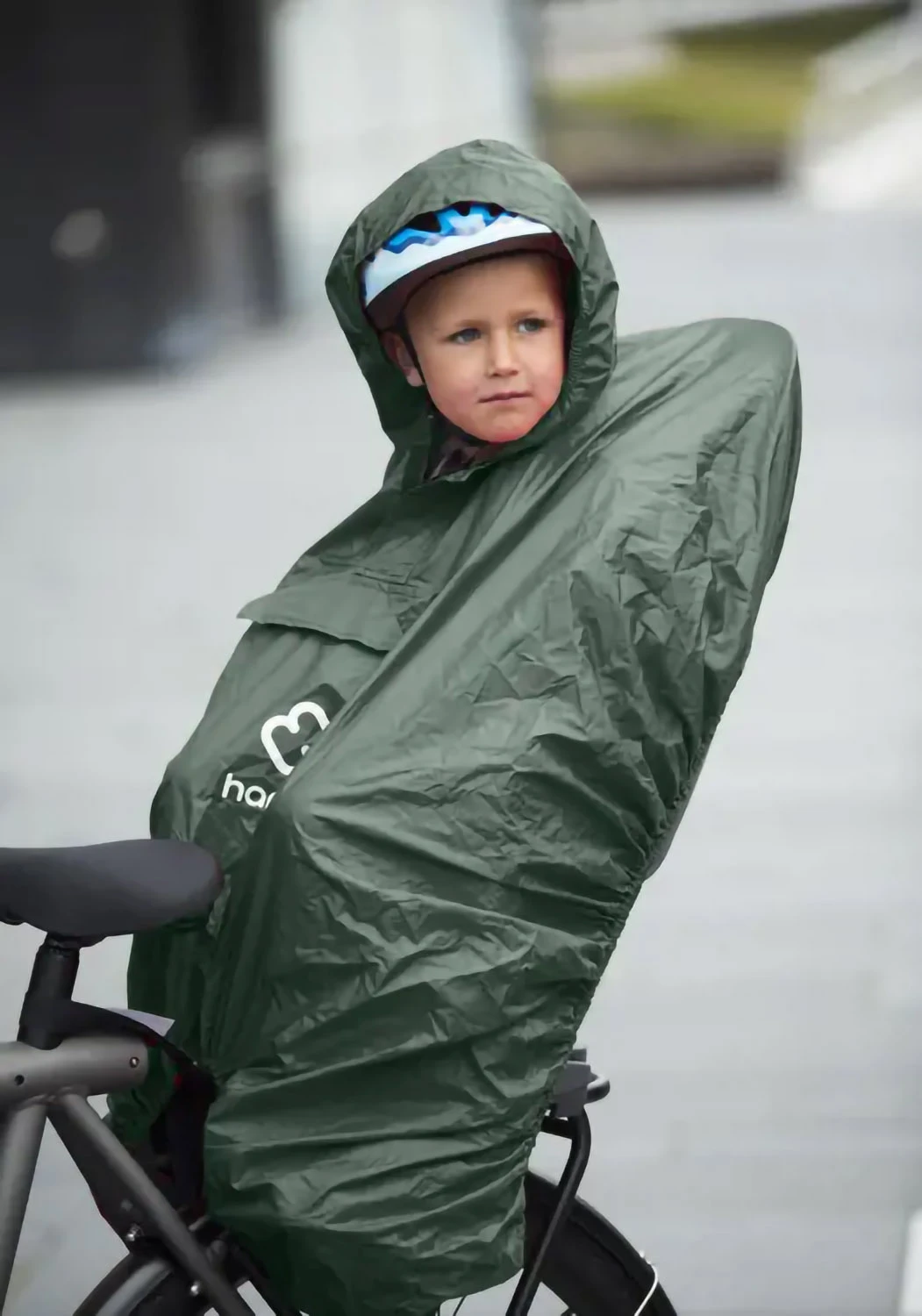 Hamax Caress rack-mounted bike seat with rain poncho fitted to protect child from wind and rain