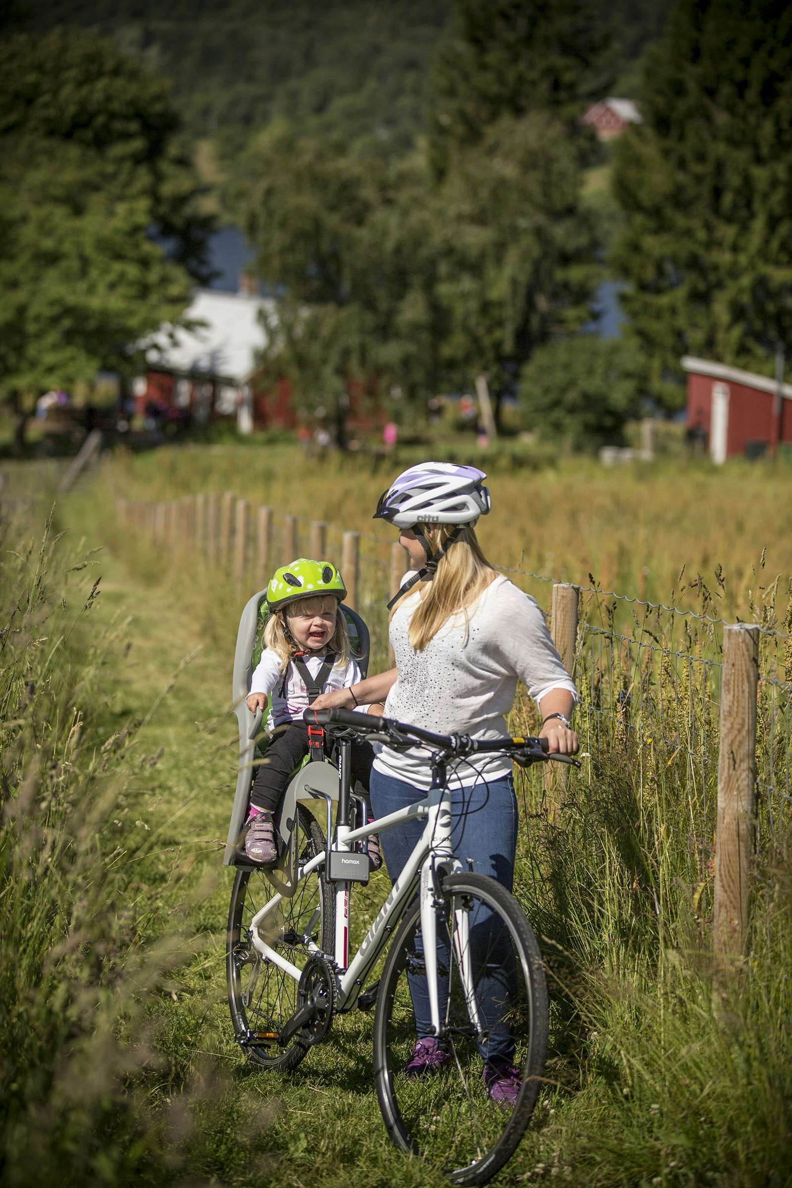 Mother and child enjoying a bike ride on a countryside path, with the child seated in a Hamax bike seat
