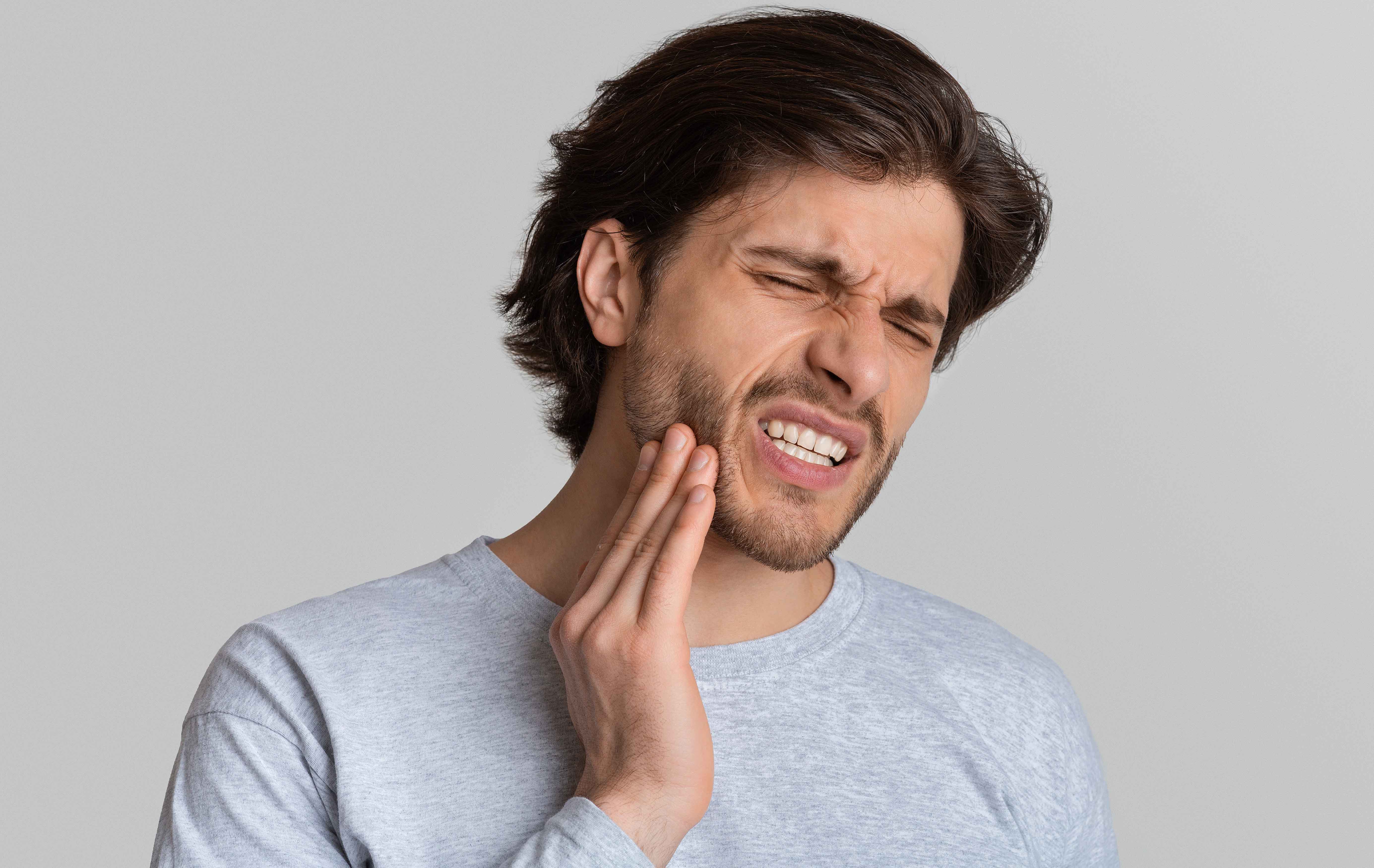 Man with toothache holding his cheek