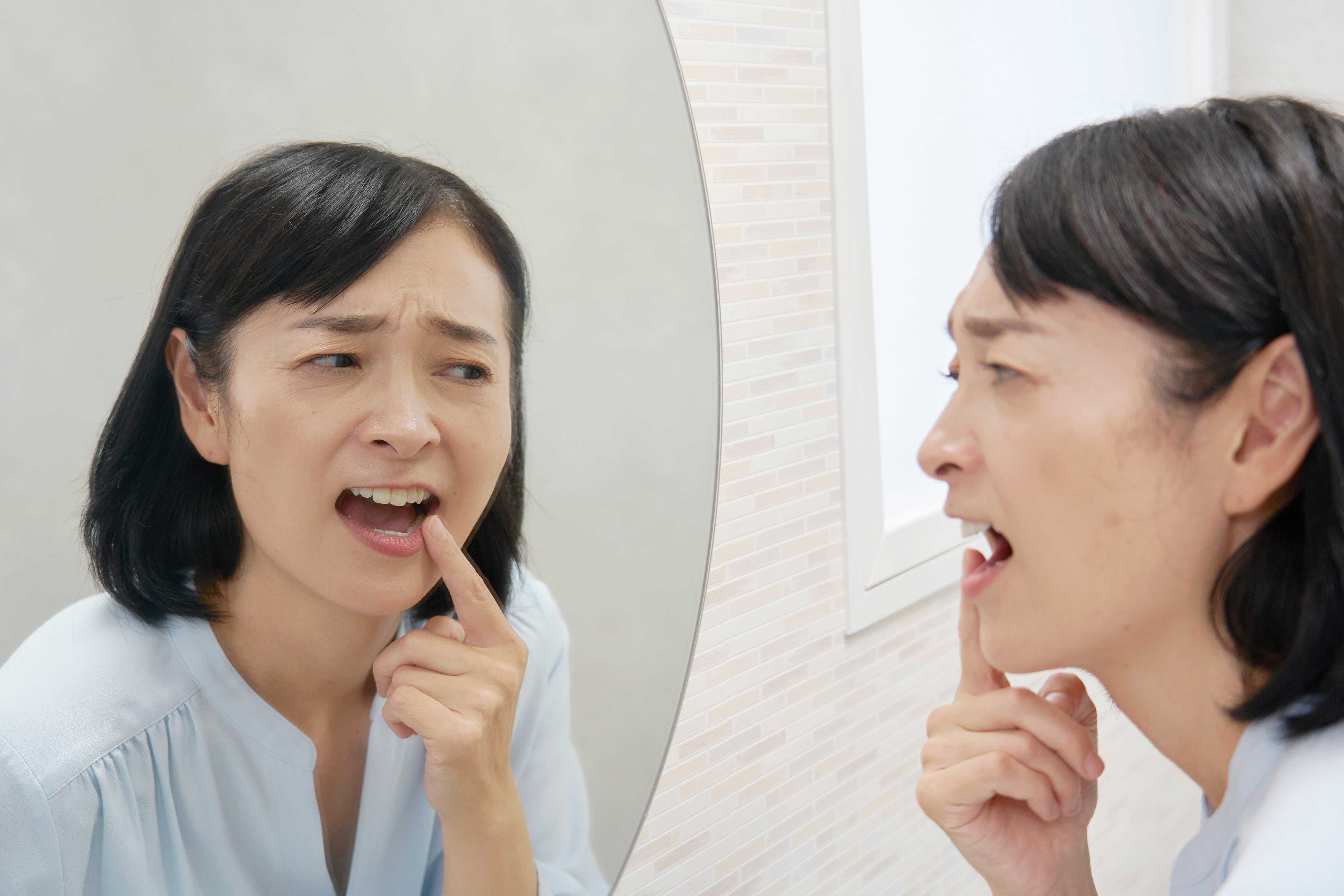 Woman looking in a mirror at her teeth