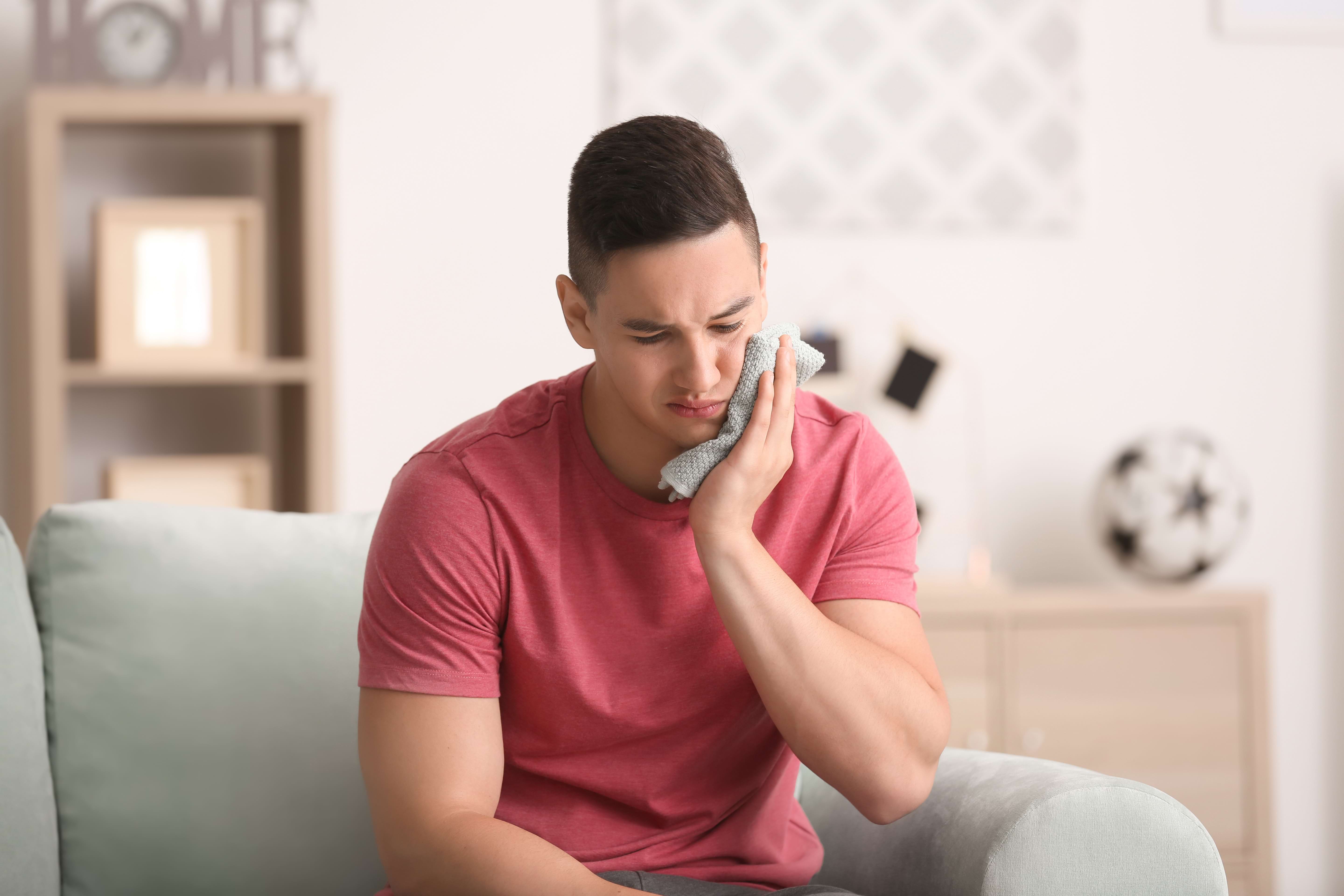 Man holding a cold compress to his cheek