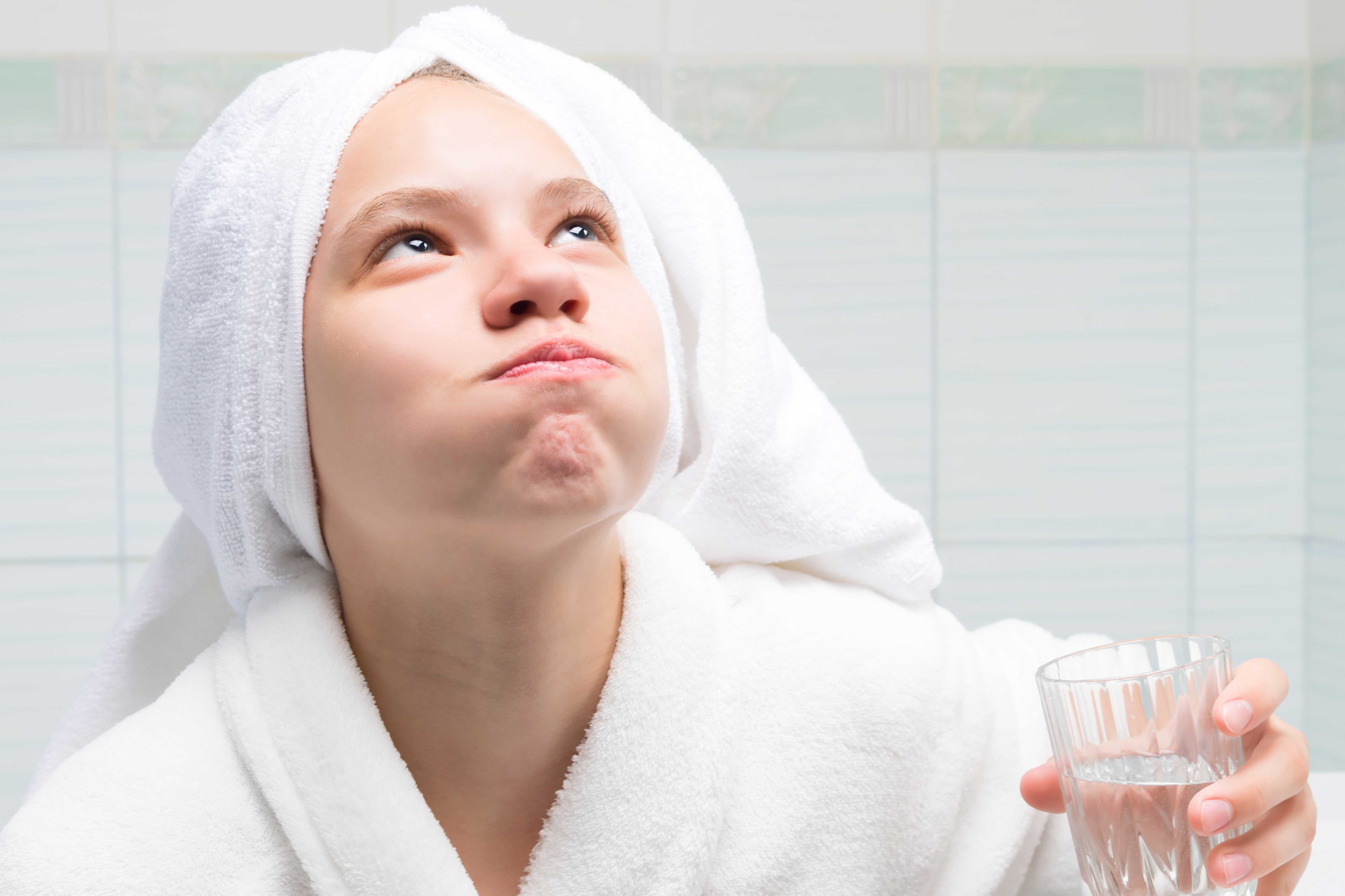 Woman in a bathroom rinsing with mouthwash