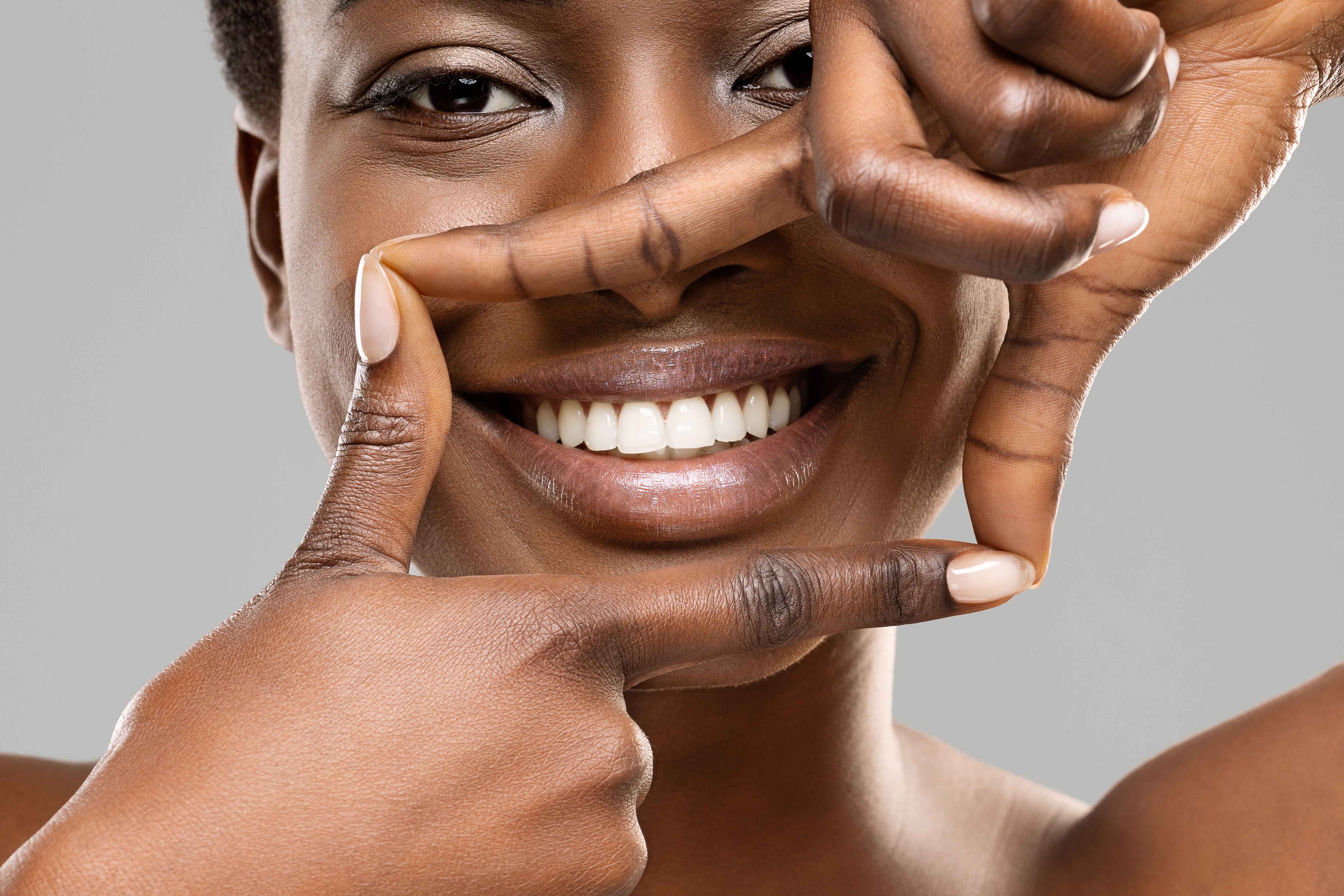 Woman smiling and framing her mouth with her hands 