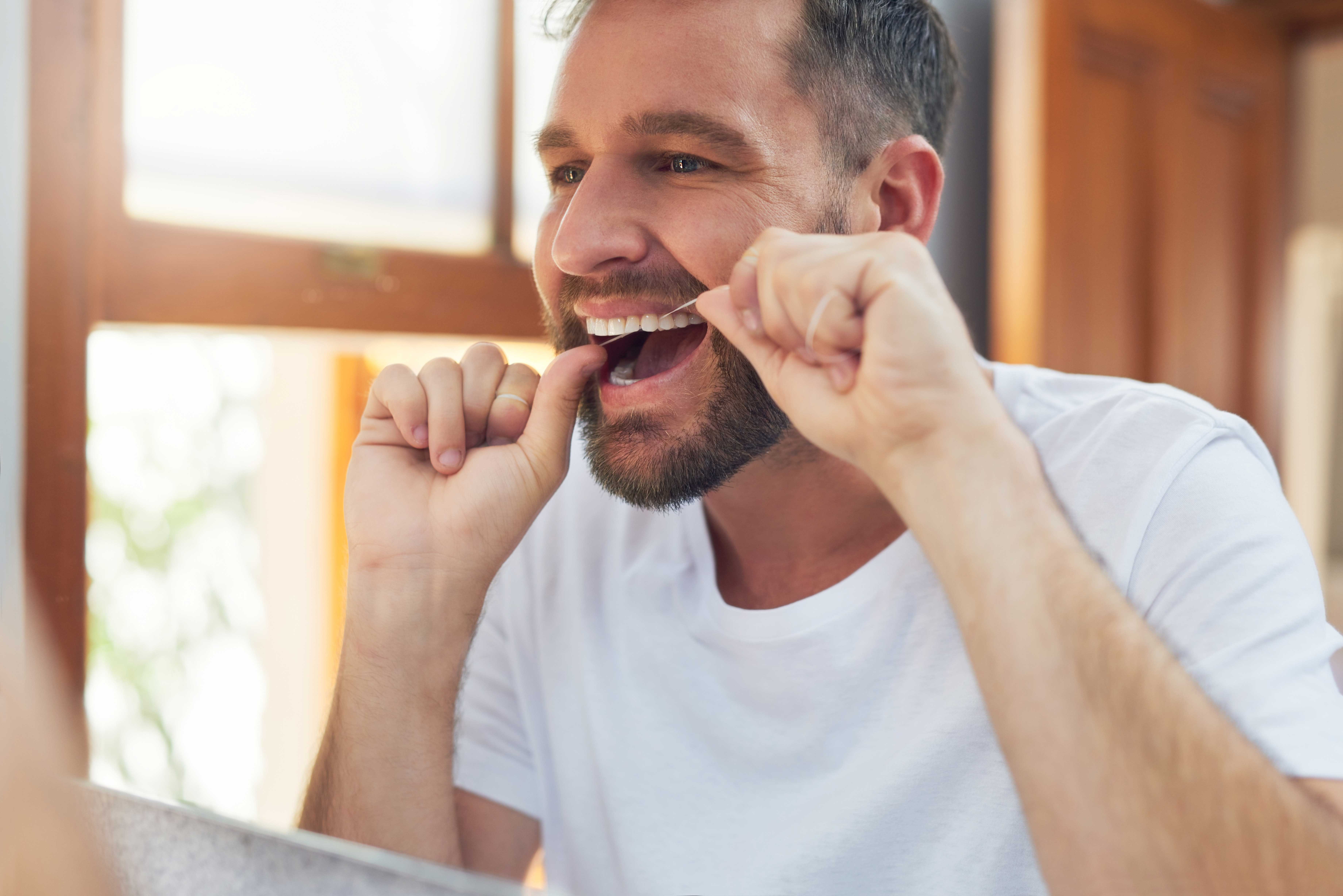Man flossing his teeth to maintain healthy gums