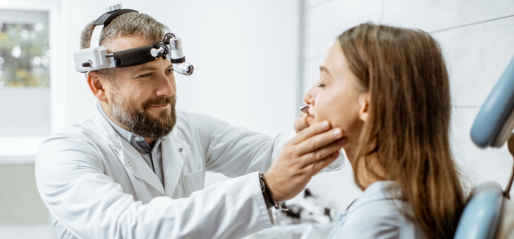 Doctor examining female patient's throat