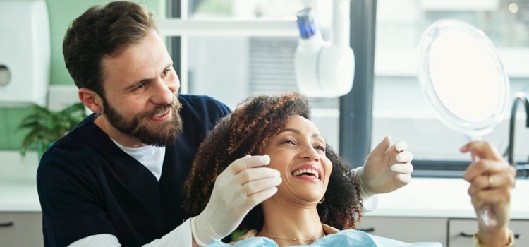 Dentist and patient smiling into mirror.