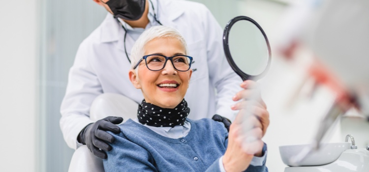 Dentist and patient smiling into mirror.