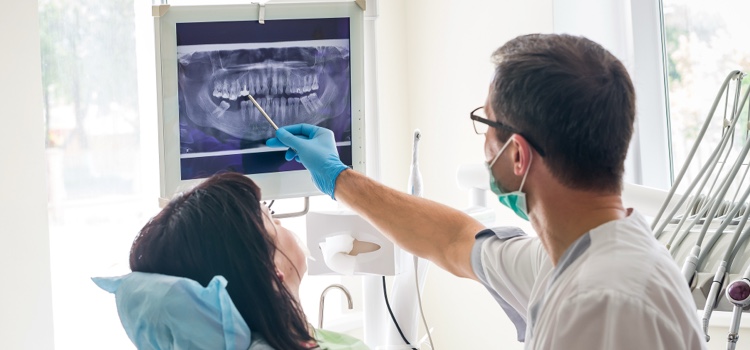 Male dentist showing female patient x-ray.