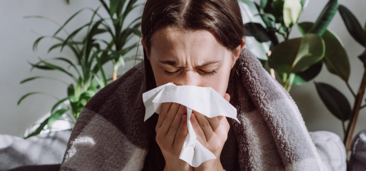 Ill young woman coughing into a tissue.