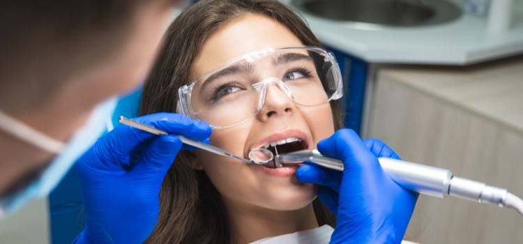 Dentist in mask filling the female patient's root canal.