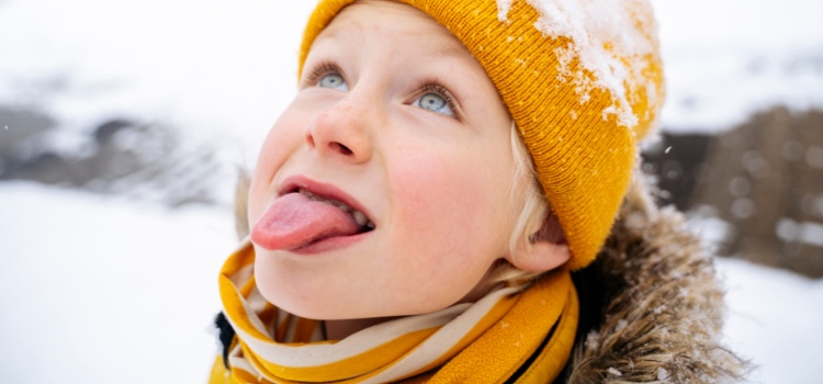 Young boy sticking is tongue out to catch the snow