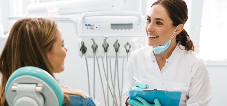 Female smiling dentist questioning female patient on her oral care regime.