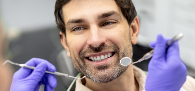Dentist examining male patient's teeth at dental clinic
