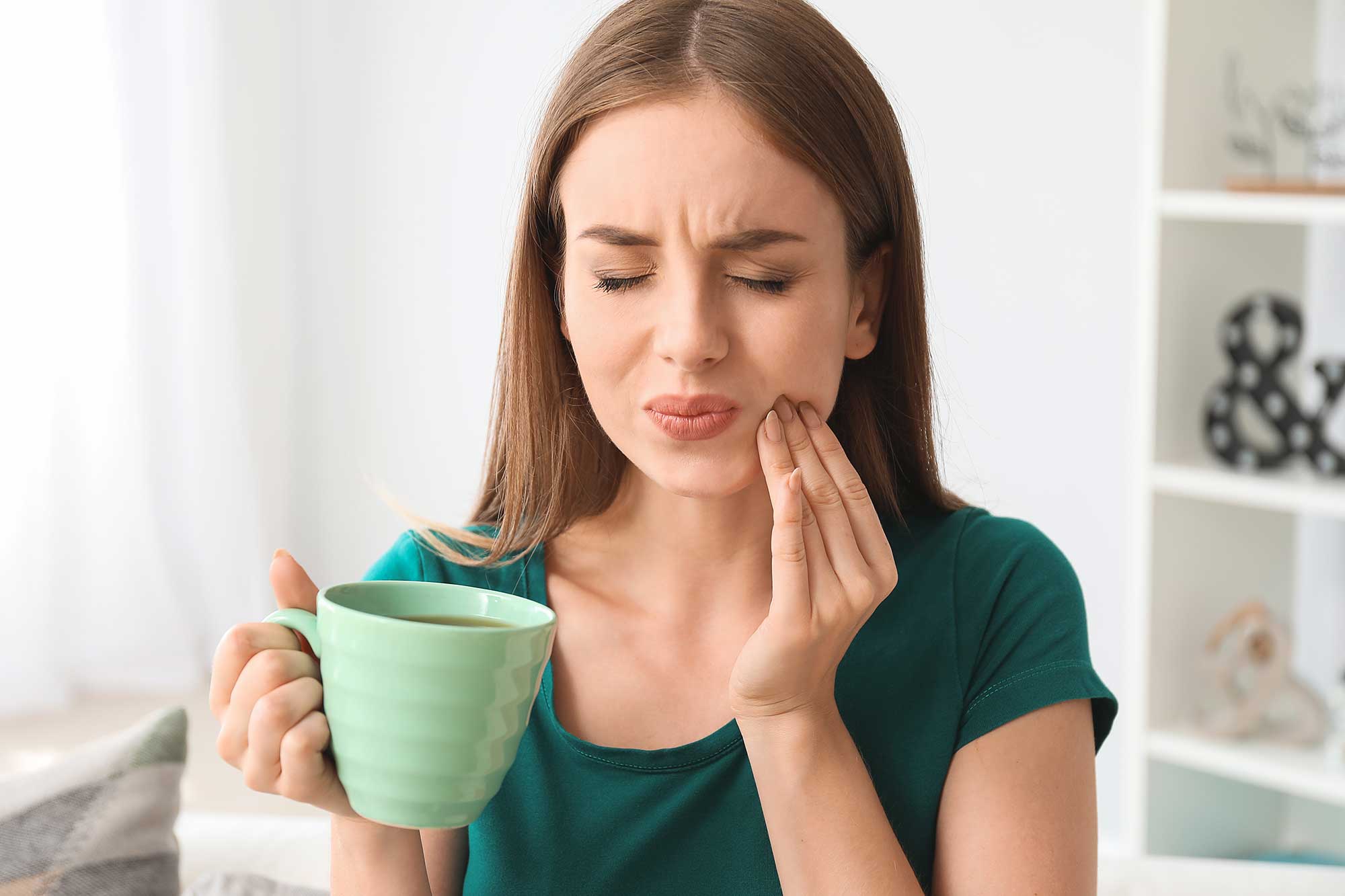 Woman experiencing teeth pain after drinking a hot drink