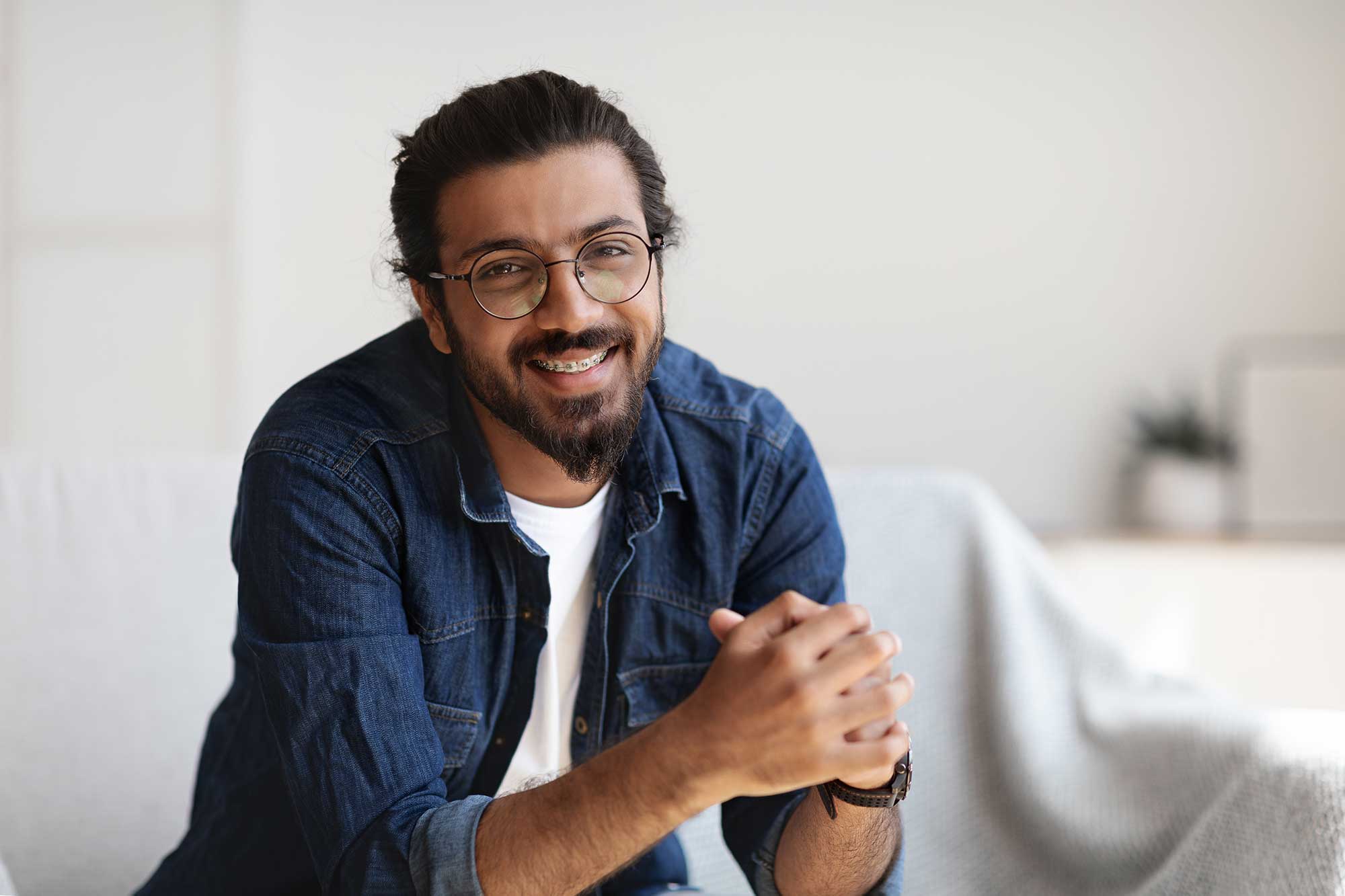 A man leaning on a counter and smiling, showing his braces