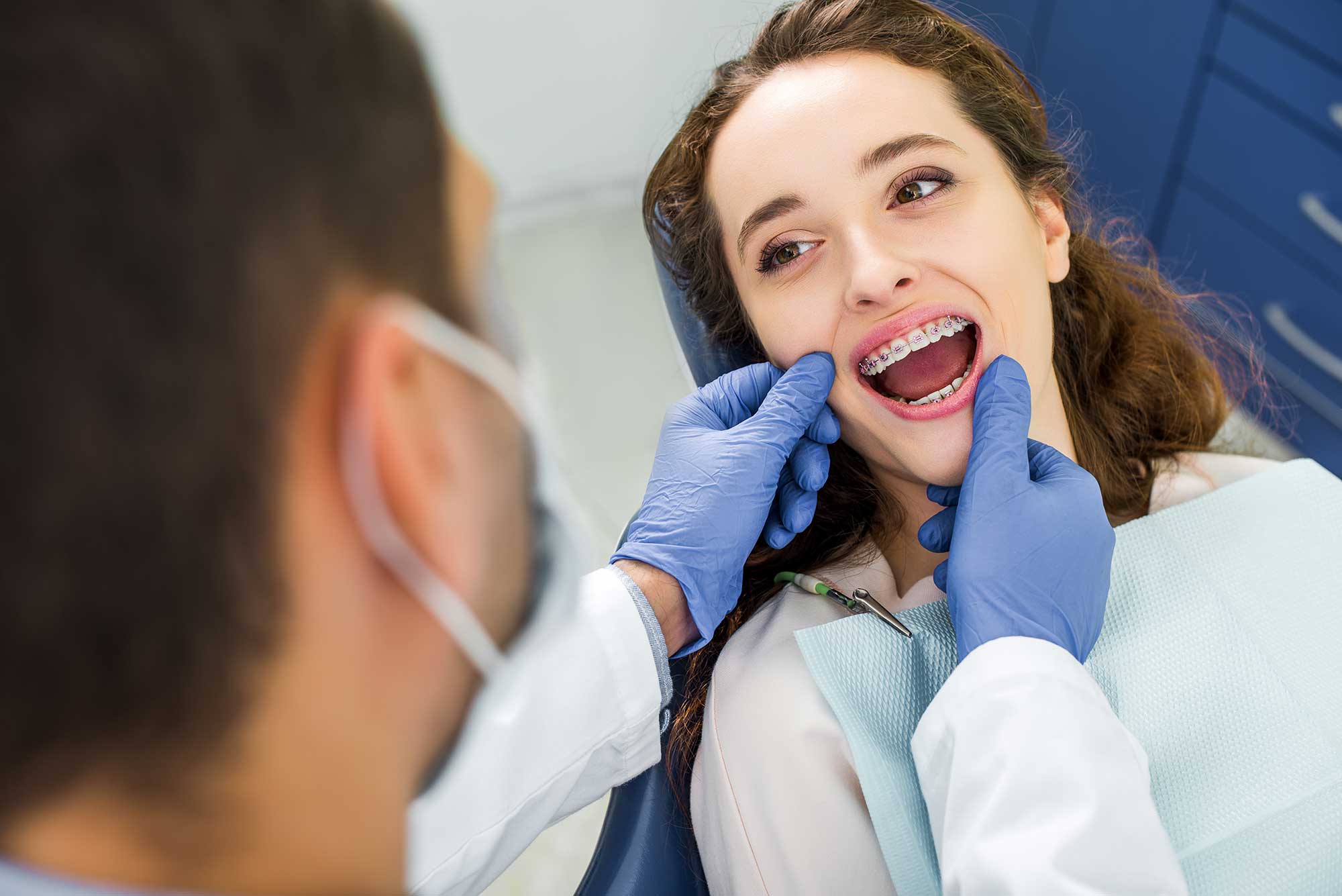 Woman lying in a dentist's chair having her braces examined by a dentist