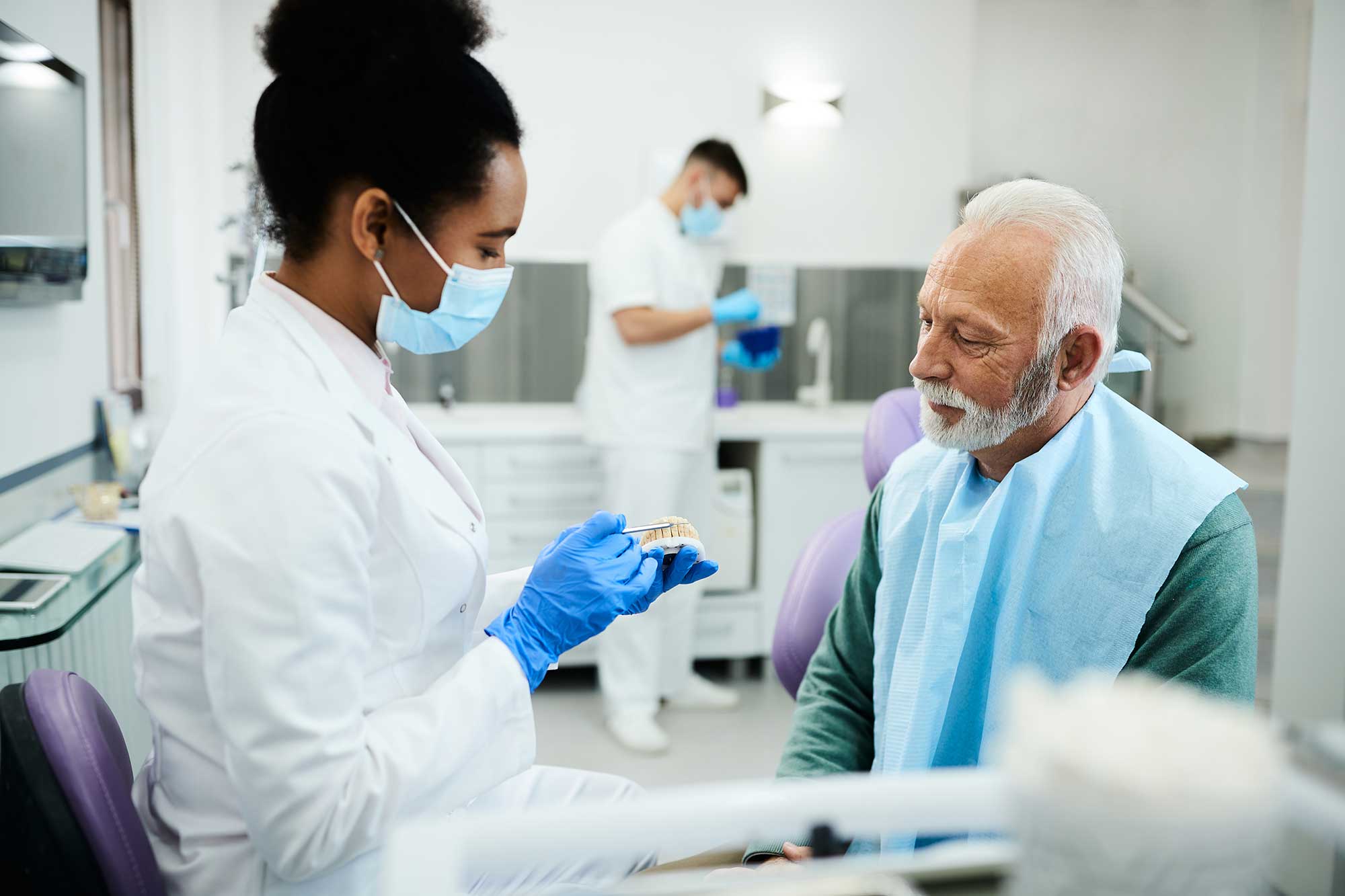 Dental professional showing a patient a model of teeth