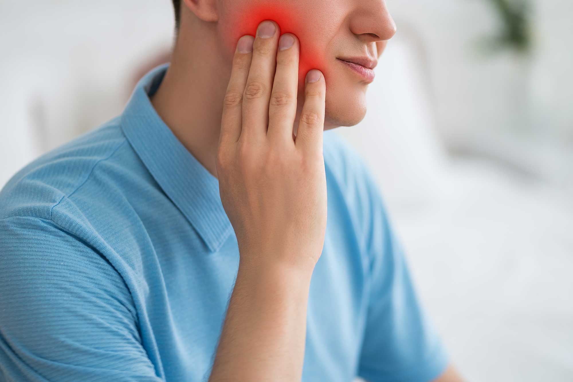 Man holding side of a red, dramatized cheek to show pain