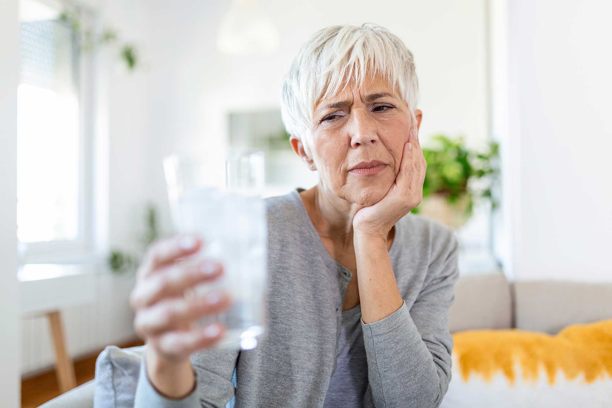 Older woman looking at a glass of water in her hand