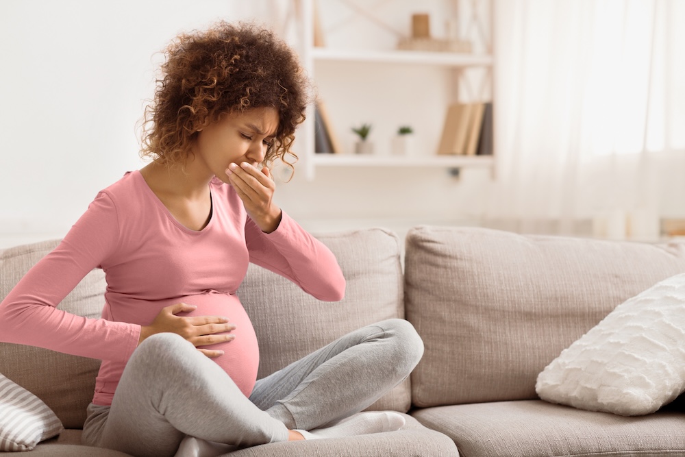 Pregnant woman on couch experiencing mouth discomfort Pregnant woman on couch experiencing mouth discomfort