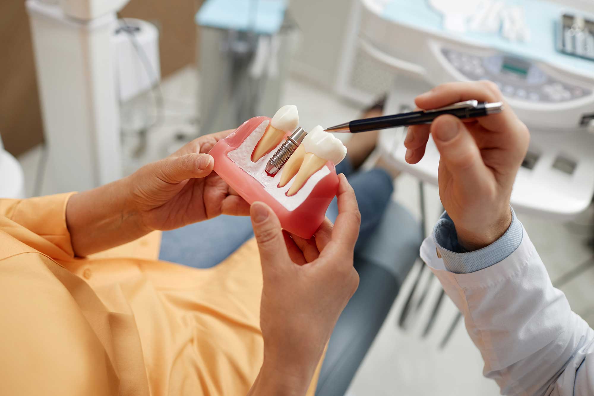 Patient holding a model of a cross-section of a dental implant