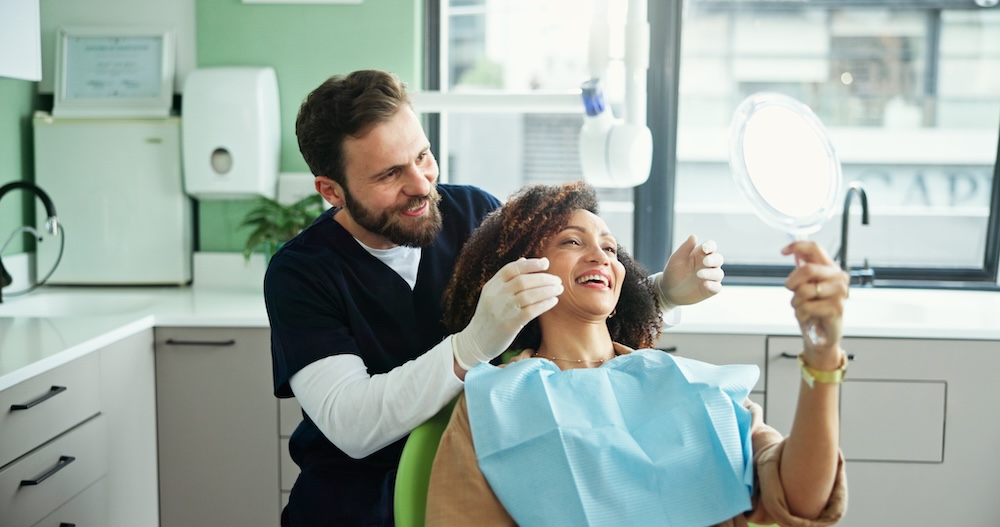 Patient looking at their whitened teeth at dental office