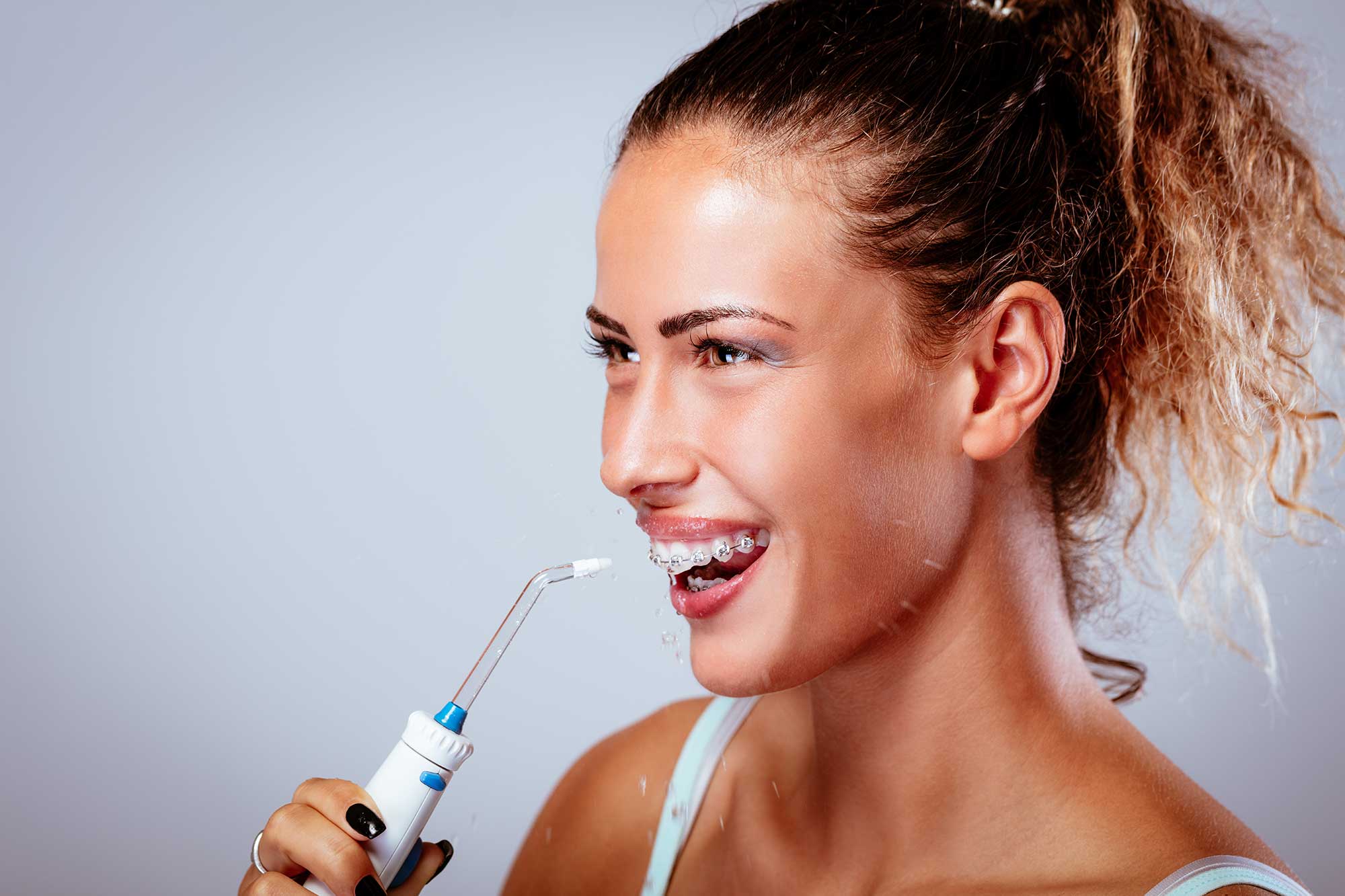 Smiling woman in braces using a water flosser image
