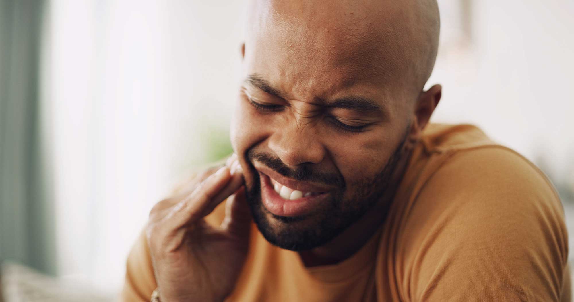 Man grimacing, experiencing wisdom teeth pain