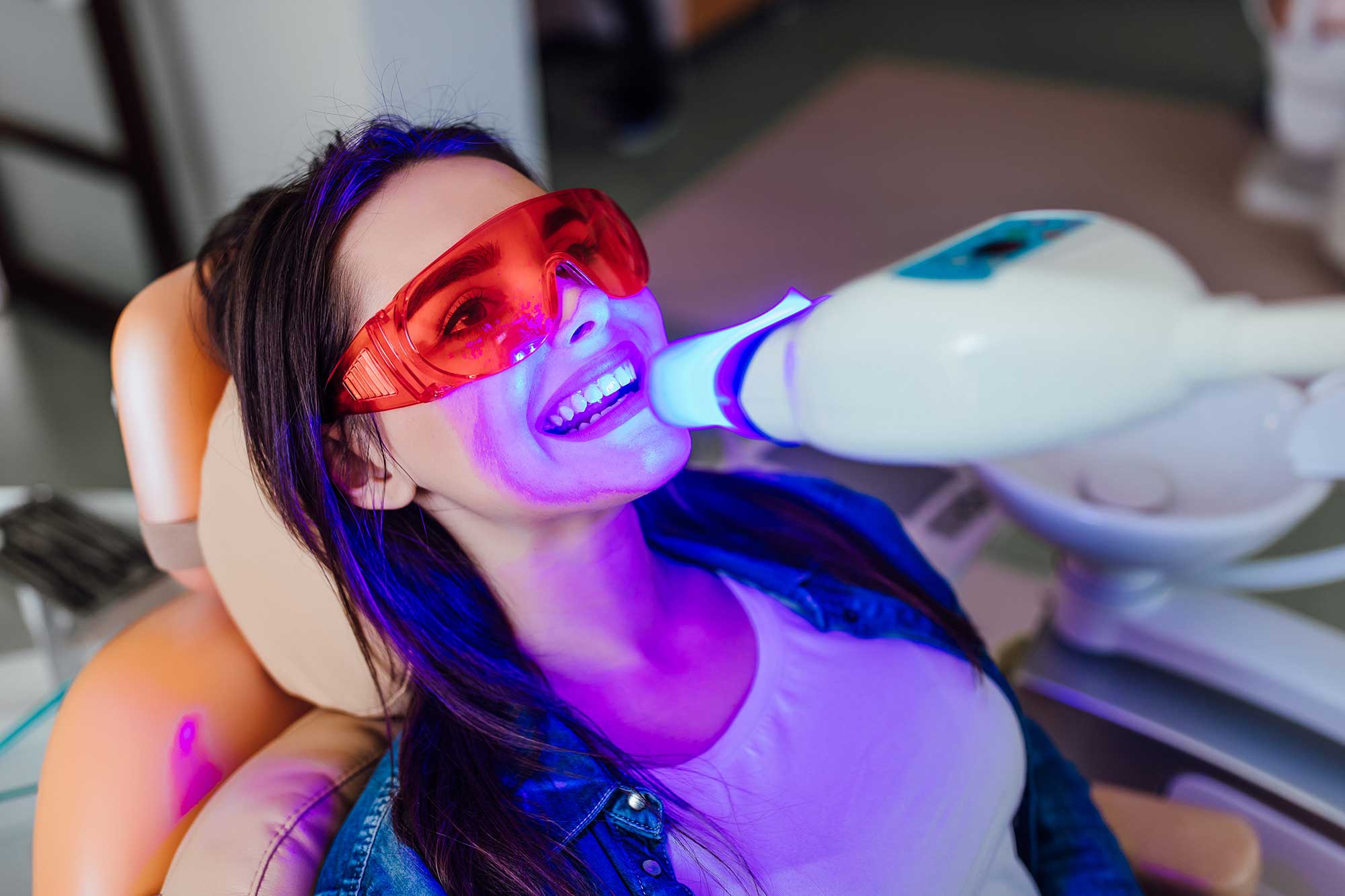 Woman bleaching her teeth at a modern office