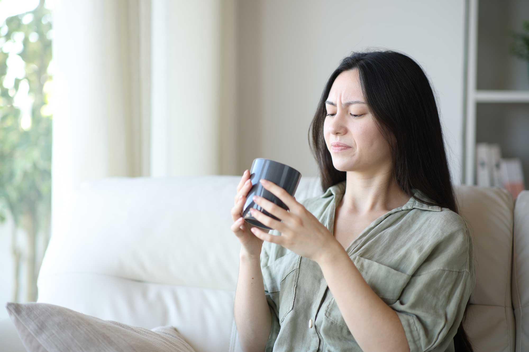 Woman grimacing after drinking a hot drink image