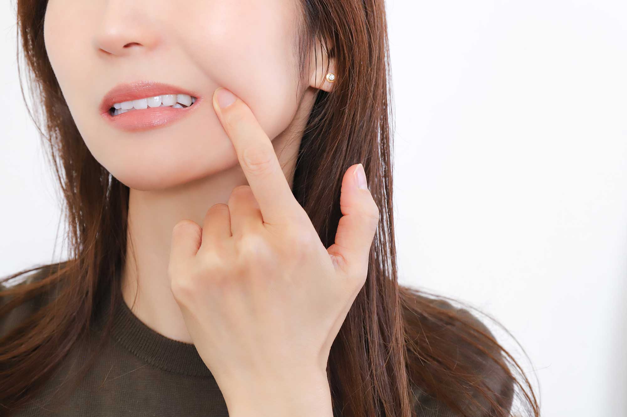 Woman grimacing with pain and holding the side of her cheek
