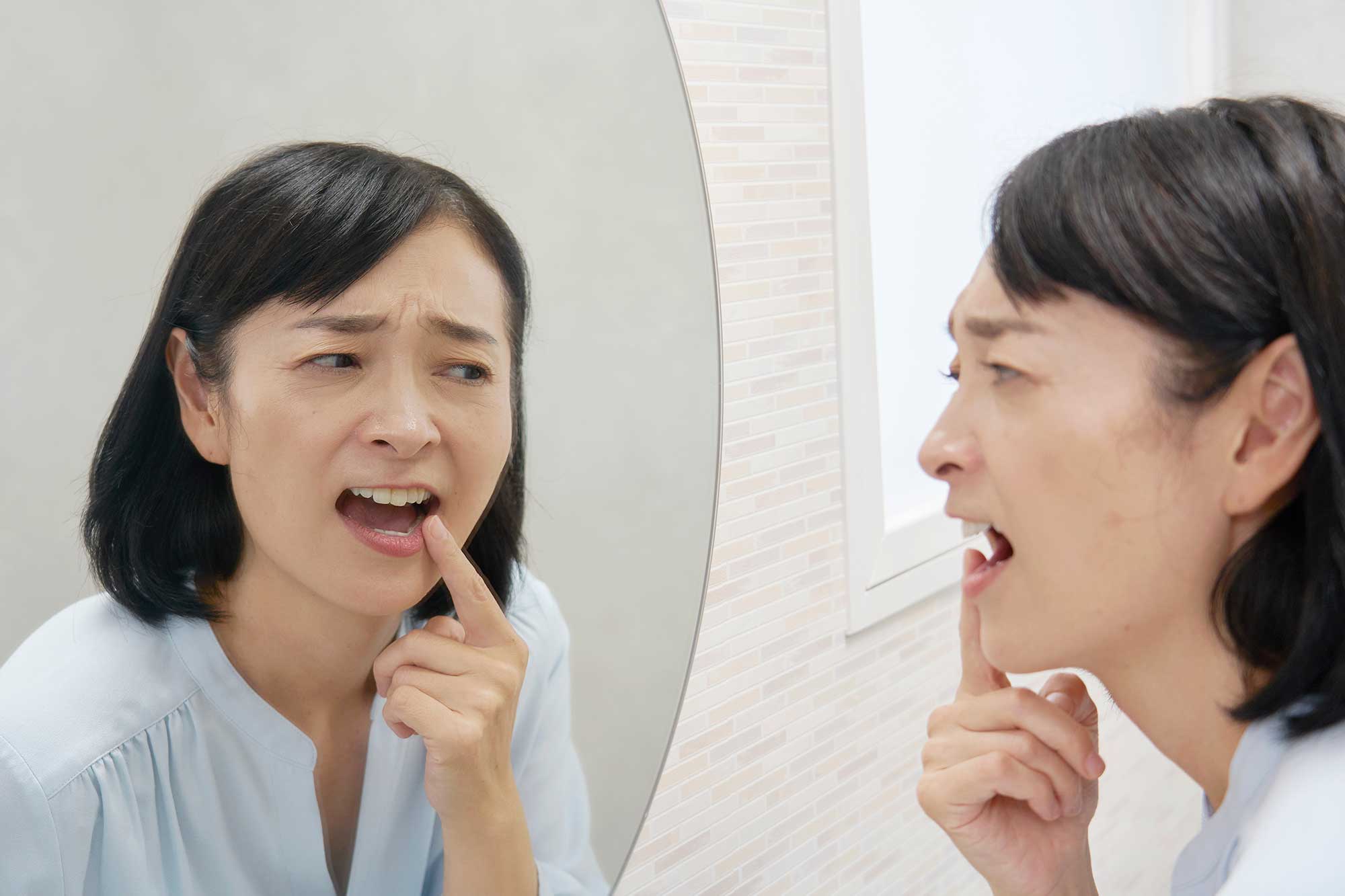 Woman inspecting a bump on her lip in a mirror