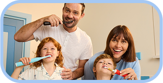 Two kids happily brushing their teeth together