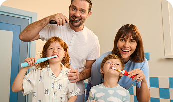 A circle of smiling kids behind a display of Oral-B’s Marvel Spider and Disney Stitch electric toothbrushes
