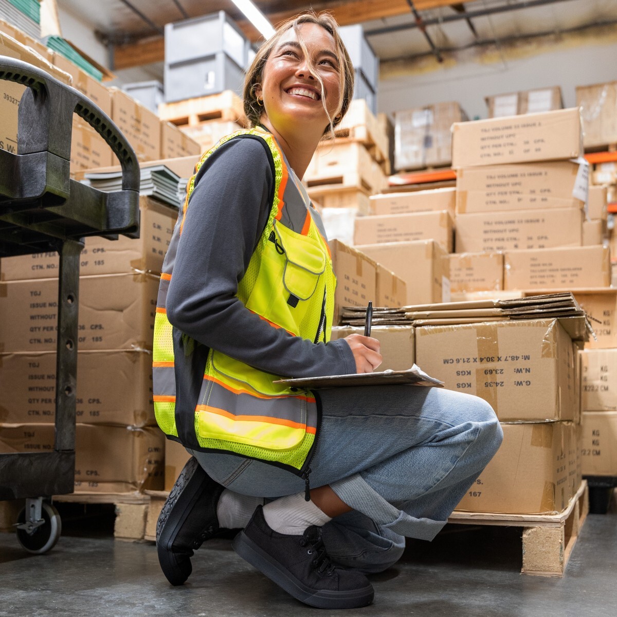 Female warehouse worker kneeling down wearing Roxy static dissipative shoes and a safety vest