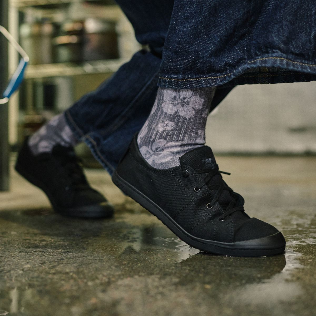 Woman wearing slip resistant soft toe work shoe kneeling over a puddle of water.