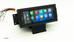 Aftermarket 1.5-DIN touchscreen radio mounted in a custom dash kit for a 1984–1989 Chevrolet Corvette (C4), displaying the Apple CarPlay home screen, with wiring harness visible, photographed on a white background