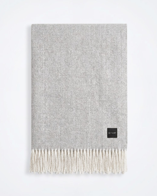 Light grey cotton‑blend throw laid flat against a plain background, showing overall texture and colour.