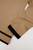lose‑up of tan knit fabric showing smooth texture and black contrast trim at sleeve and hem.