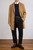 Man wearing camel wool‑blend overcoat over navy sweater and white shirt, styled with brown trousers and Chelsea boots.