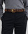 Model wearing Le Camp antique brown leather belt with brass buckle over gray sweater and black trousers.