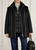 Model wearing the Nenette eco‑friendly black parka paired with casual trousers, demonstrating the fit and overall silhouette.