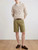 Model wearing Exibit men’s khaki stretch cotton shorts, showing the modern above‑knee fit and casual summer styling.