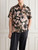 Model wearing the Why Not Brand printed short sleeve shirt paired with casual trousers