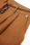 Close-up of pleated detailing and linen fabric texture on the shorts.